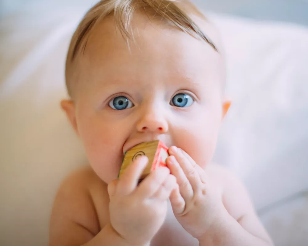 Baby met speelgoedje in mond